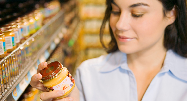 Eine Frau liest das Etikett eines Bio-Produkts in einem Lebensmittelgeschäft.